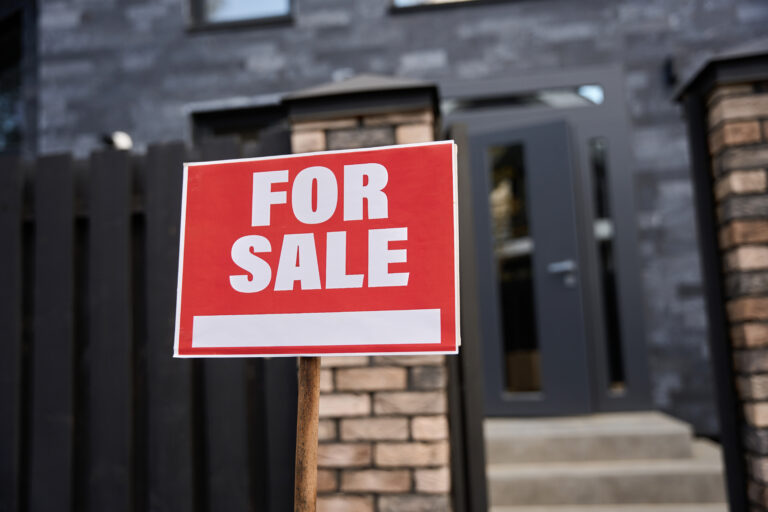 Near the house there is a red sign for sale